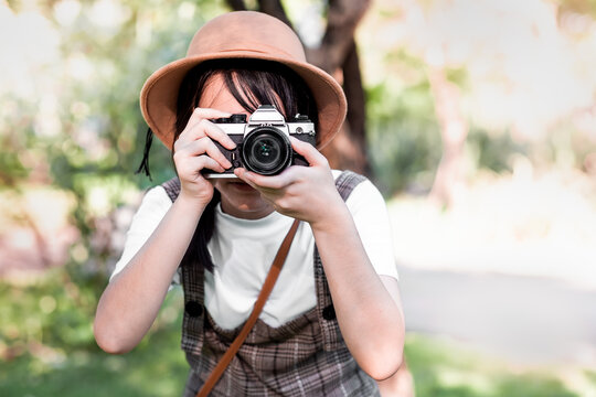 Portrait of a beautiful teenager girl making photo with camera in garden, 