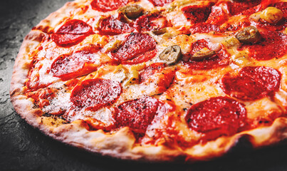 Hot Pepperoni Pizza with Mozzarella cheese, salami, Tomato sauce, pepper, Spices. Italian pizza on Dark grey black slate background