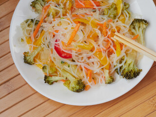 Glass noodle salad with vegetables and pepper on a wooden table.
