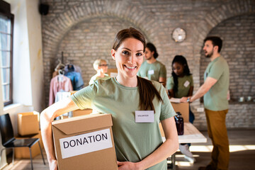 Portrait of female volunteer holding a box with donation. - obrazy, fototapety, plakaty