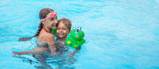 banner with happy brother and sister swim in the pool. Smiling girl and boy are playing in the pool. The concept of family vacation or relaxation in the pool or the sea.