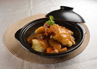 deep fried grouper fish fillet seafood in black hot clay pot with vegetables and mushroom in dark soy sauce white background premium asian halal menu