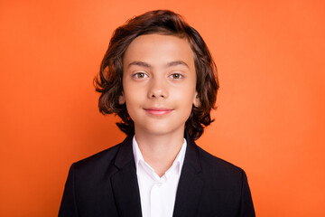 Photo of young brunette calm peaceful boy wear formalwear suit uniform isolated on orange color...