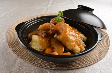 deep fried grouper fish fillet seafood in black hot clay pot with vegetables and mushroom in dark soy sauce white background premium asian halal menu
