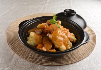 deep fried grouper fish fillet seafood in black hot clay pot with vegetables and mushroom in dark...