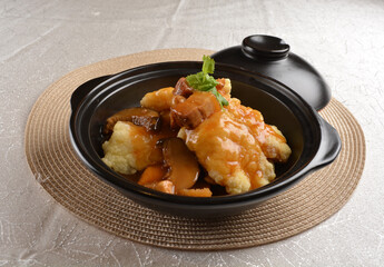 deep fried grouper fish fillet seafood in black hot clay pot with vegetables and mushroom in dark soy sauce white background premium asian halal menu