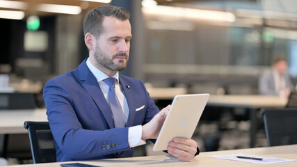 Middle Aged Businessman using Tablet at Work