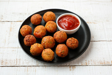 Fried potato cheese balls or croquettes cottage cheese Paneer ball with tomato sauce on black plate over dark background. fast food, top view meat ball.