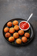 Fried potato cheese balls or croquettes cottage cheese Paneer ball meat balls with tomato sauce on black plate over dark background. fast food, top view 