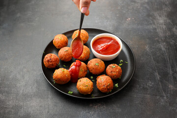 Hand serving Fried potato cheese balls or croquettes cottage cheese Paneer ball meat balls with...