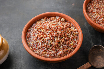 Ayurvedic porridge, Karkidaka Kanji herbal gruel in clay pot black background Kerala South India. Ayurveda diet health drink for immunity, cleanse the body. Top view medicinal porridge Indian veg food