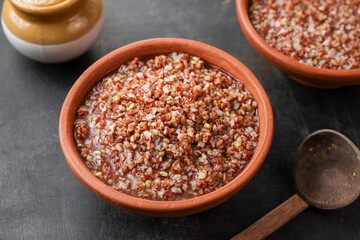 Ayurvedic porridge, Karkidaka Kanji herbal gruel in clay pot black background Kerala South India. Ayurveda diet health drink for immunity, cleanse the body. Top view medicinal porridge Indian veg food