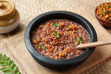 Ayurvedic porridge, Karkidaka Kanji herbal gruel in clay pot black background Kerala South India. Ayurveda diet health drink for immunity, cleanse the body. Top view medicinal porridge Indian veg food