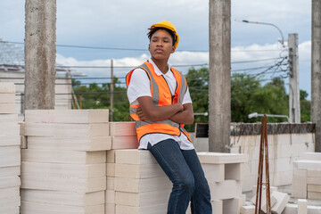 African American male worker sits on a house under construction in a housing estate under...