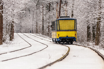 An old tram moving through a winter forest