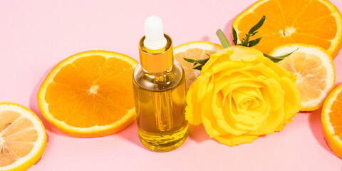 Vitamin C serum bottle with dropper on pink background with orange citrus slices