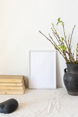 Home decor mock-up, blank picture frame near white painted concrete wall , black earthenware jug...