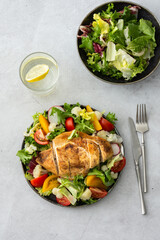 Delicious hearty lunch, chicken breast baked with spices and a mix of salad with tomatoes, radishes and cauliflower, top view, copy space