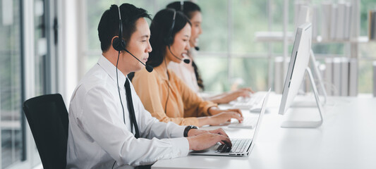 Team of call center staff in Asia wears headphones with a microphone. Smile while serving customers...