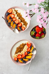 Delicious healthy breakfast, granola with yogurt and sweet fruit, banana and strawberry, blueberry and peach