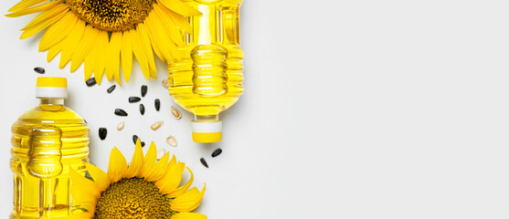 Plastic bottles with sunflower oil, fresh yellow sunflowers, sunflower seeds on gray background....