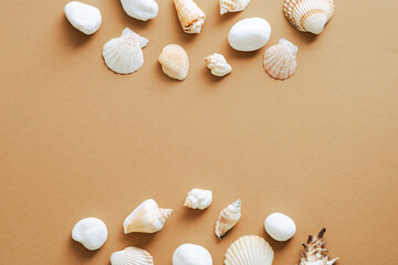 Frame made of seashells on sand color background. Summer, vacation concept. Flat lay, top view, overhead.