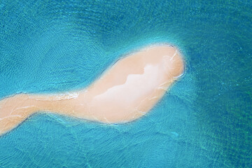 Aerial view of the sandy beach island in the transparent blue sea with waves. Summer vacation. Tropical landscape with white sand and ocean. Top view.