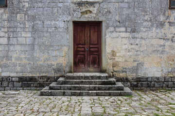 obsolete brown wooden door and with lock stone bricks steps in the front of ancient building