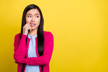 Photo of minded young doubtful woman bite teeth nail look empty space isolated on yellow color...
