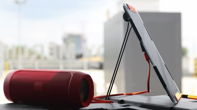 Bluetooth speaker connected to portable solar panel. Portable solar charging technology idea.