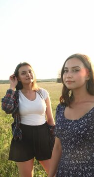 Two sisters walk in nature and communicate. They take pictures at sunset. High quality photo