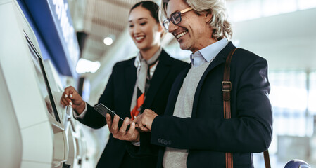 Businessman doing self check in on machine with flight attendant © Jacob Lund
