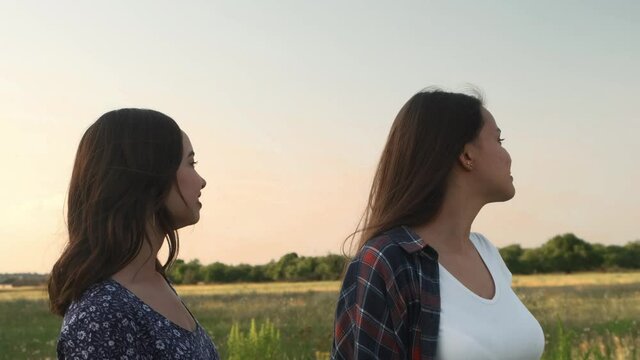 Two sisters walk in nature and communicate. They take pictures at sunset. High quality photo