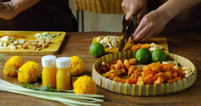 Close up of mother teaching her daughter how to prepare traditional homemade Jamu drink- Indonesian herbal beverage with natural ingredients: turmeric, ginger, lime, lemongrass, tamarind