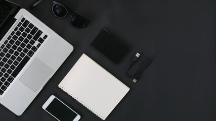 Top View laptop hardrive smartphone eyeglass notebook on black background