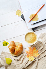 Cup of coffee with autumns leaves, diary and book template on the white wooden texture. Back to school. September, October. Write and read, study  in relaxing atmosphere. Autumn frame on white floor