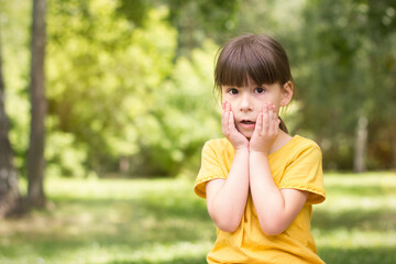 Amased petite fille dans un t-shirt jaune dans un parc