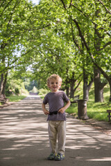 A walk in the park of a curly-haired boy. Sunny weather, the park is all in multi-colored colors