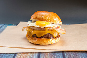 Beef burger with lots of cheddar cheese, white onion slices, fried bacon and fried egg to dip the...