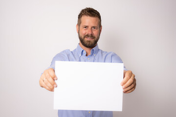 Portrait of happy smiling young business man showing blank signboard over white background.