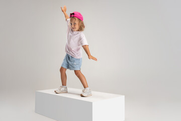 Dancing hip-hop. Portrait of little preschool Caucasian girl in casual clothes isolated over white...