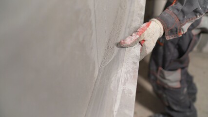 Plasterer using screeder smoothing putty plaster mortar on wall. Smoothing out putty on the wall.