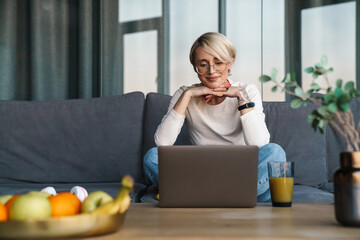 Smiling mod aged blonde woman studying online
