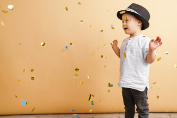 White boy with down syndrome in hat playing with confetti
