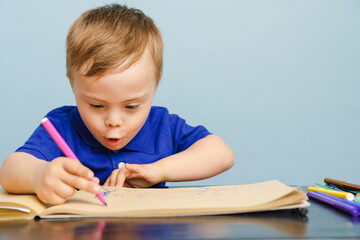 White boy with down syndrome drawing in sketchbook