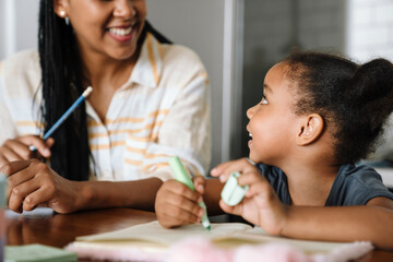 Black woman and her daughter smiling and writing in exercise books
