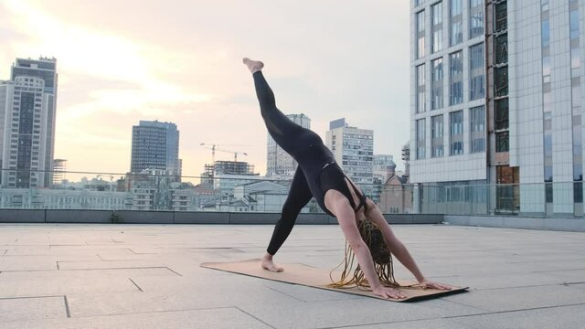 Fitness woman practices yoga outdoots at urban spaces