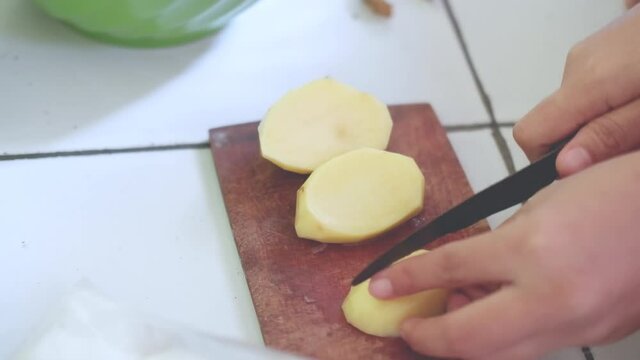 hand using knife to cut the potatoes.