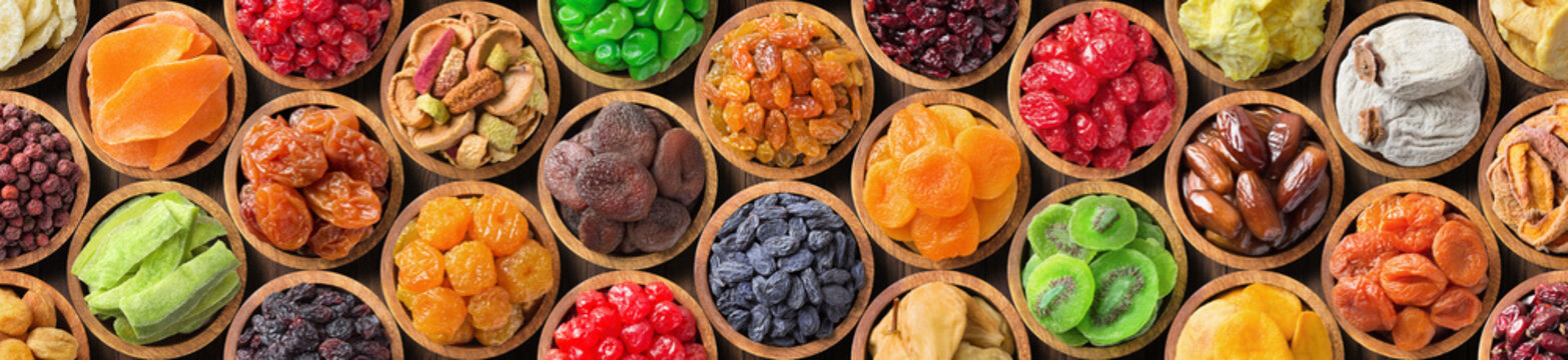 various dried fruits and berries in bowls, top view. panoramic food background.
