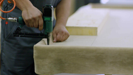 Close up on hands of furniture maker using mattress sewing machine